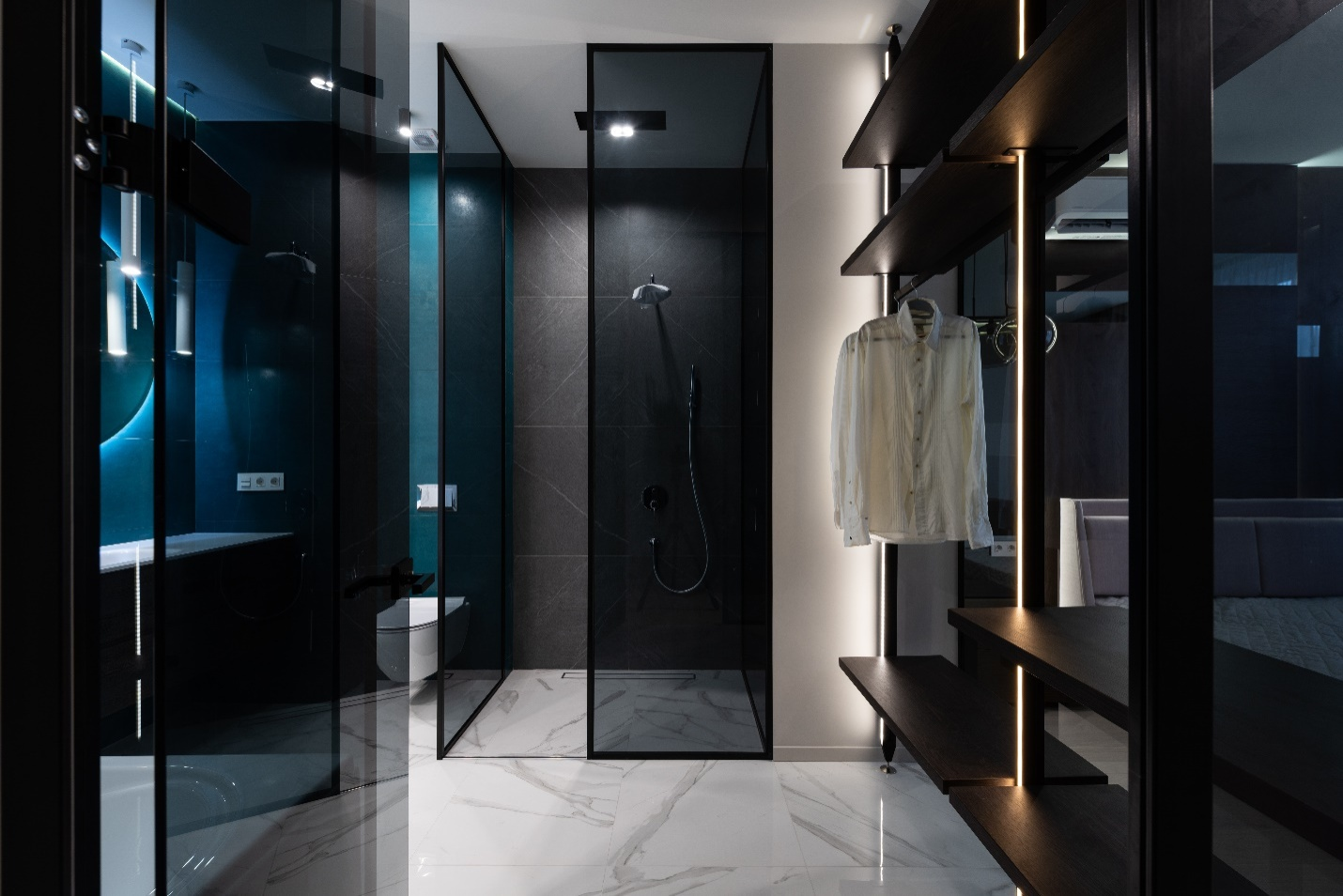 A bathroom with black-colored glass panels in front of the shower and wardrobe.