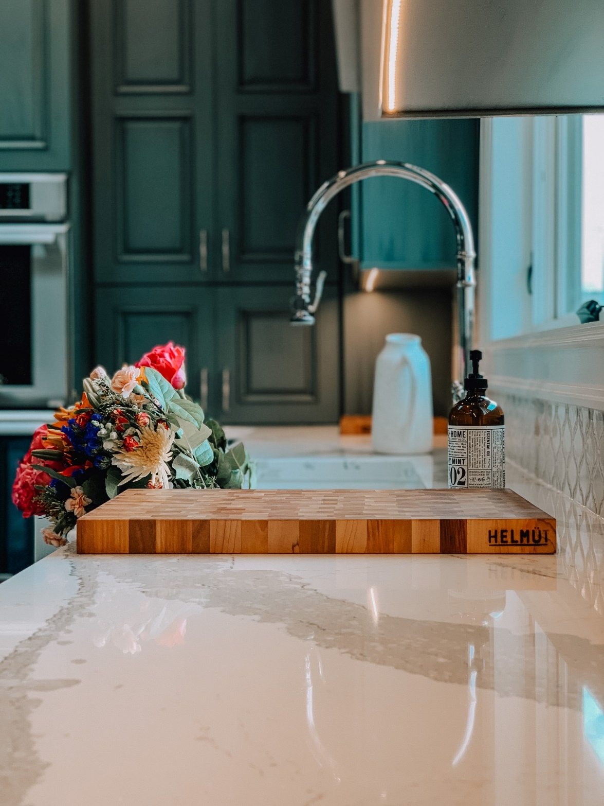 A bouquet of flowers and wooden chopping board rest on a glistening custom quartz countertop