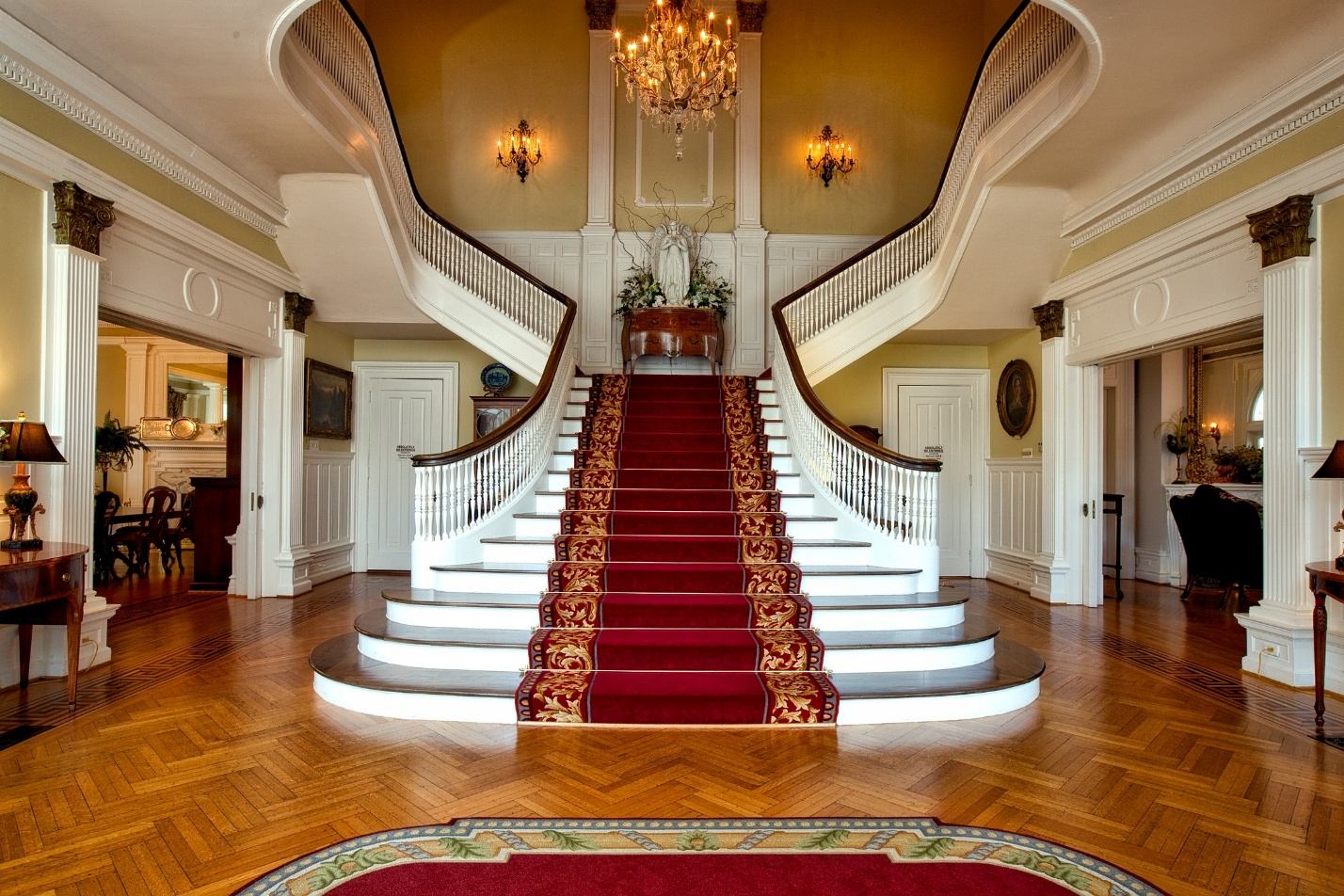 A white bifurcated staircase with a red carpet laid across the middle