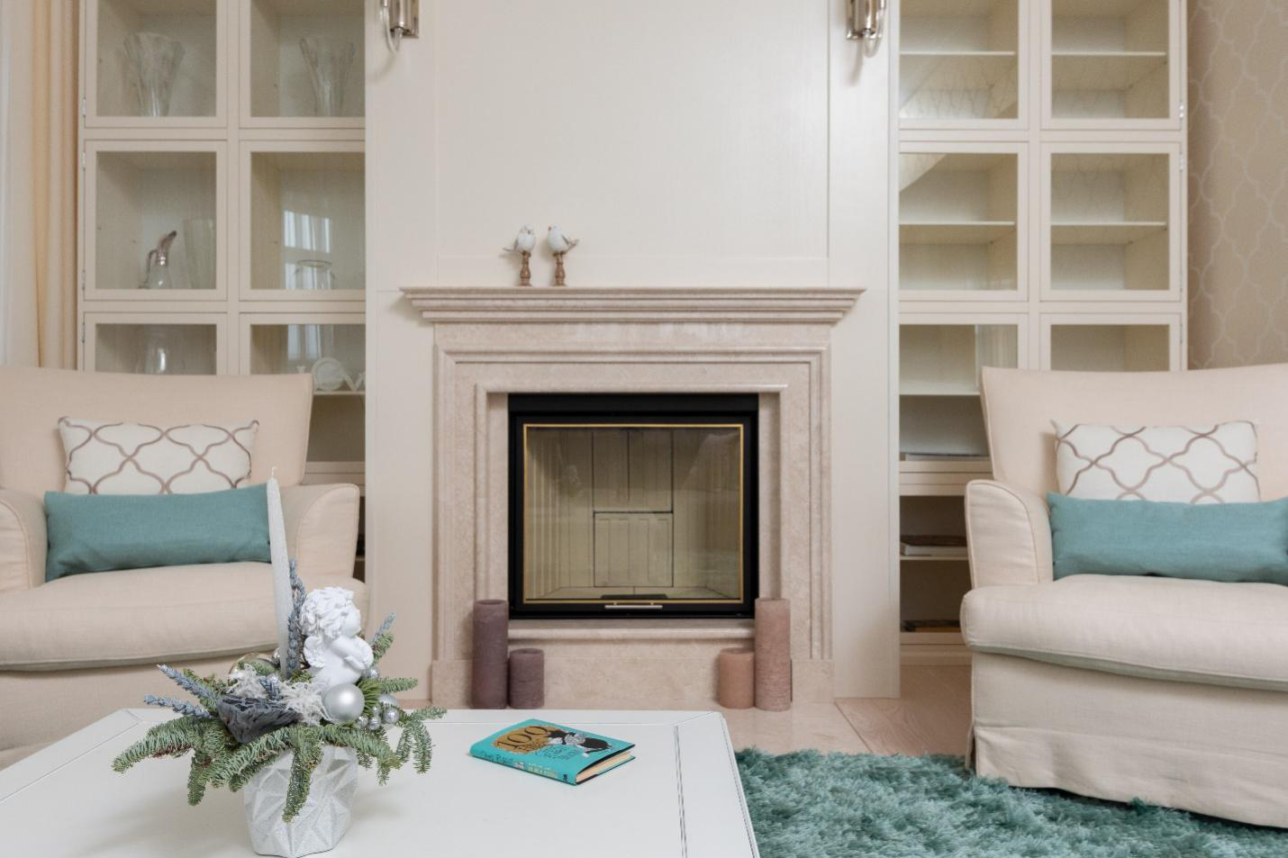 A fireplace is the focal point of a living room, flocked by two armchairs