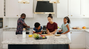 A family works together in the kitchen, preparing food on the countertop