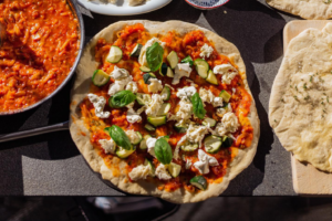 Flatbreads and pizzas sit on an outdoor kitchen countertop