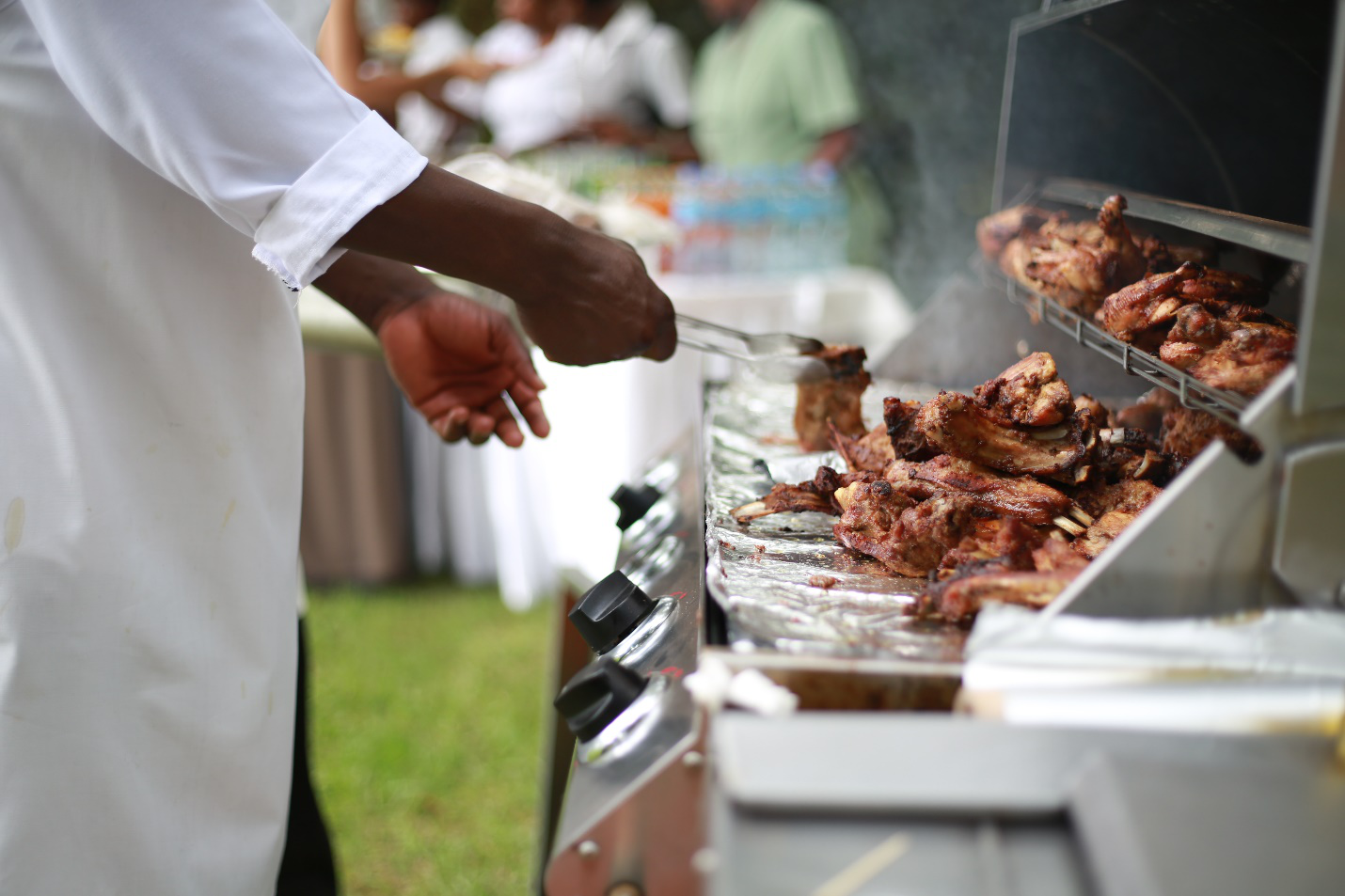 A man prepares to move the meat from the barbeque to the outdoor kitchen countertop