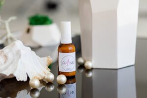 A seashell, pearls, toiletries, and décor sit on a bathroom vanity top.