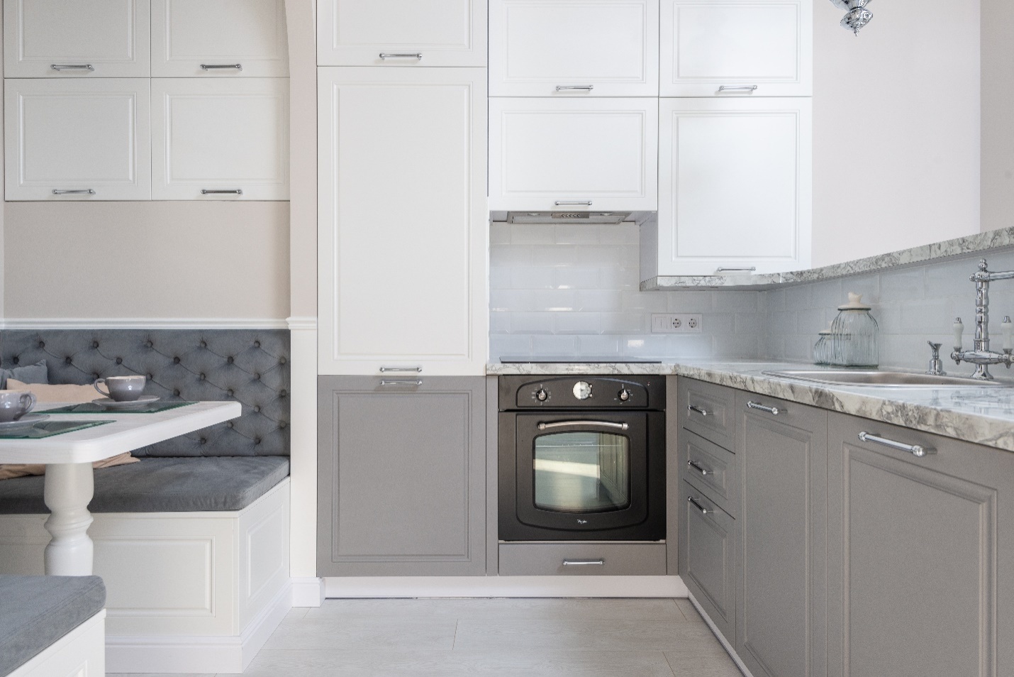 A white and grey kitchen with marble countertops