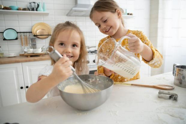 Two young girls baking in a kitchen