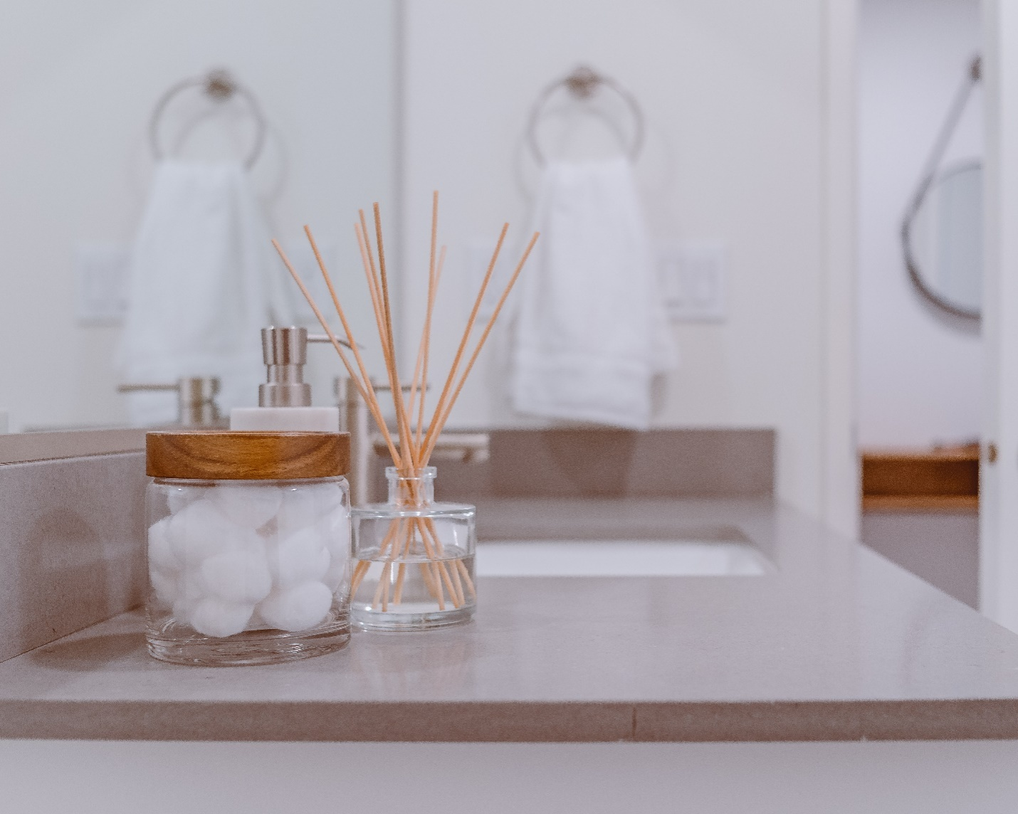 Cottons and a diffuser placed on a bathroom countertop.