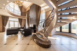 An image of a luxury home with black sofas and a curved or spiral staircase Image caption: Spiral staircase design