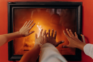 An image showing hands taking the warmth from a fireplace with a screen