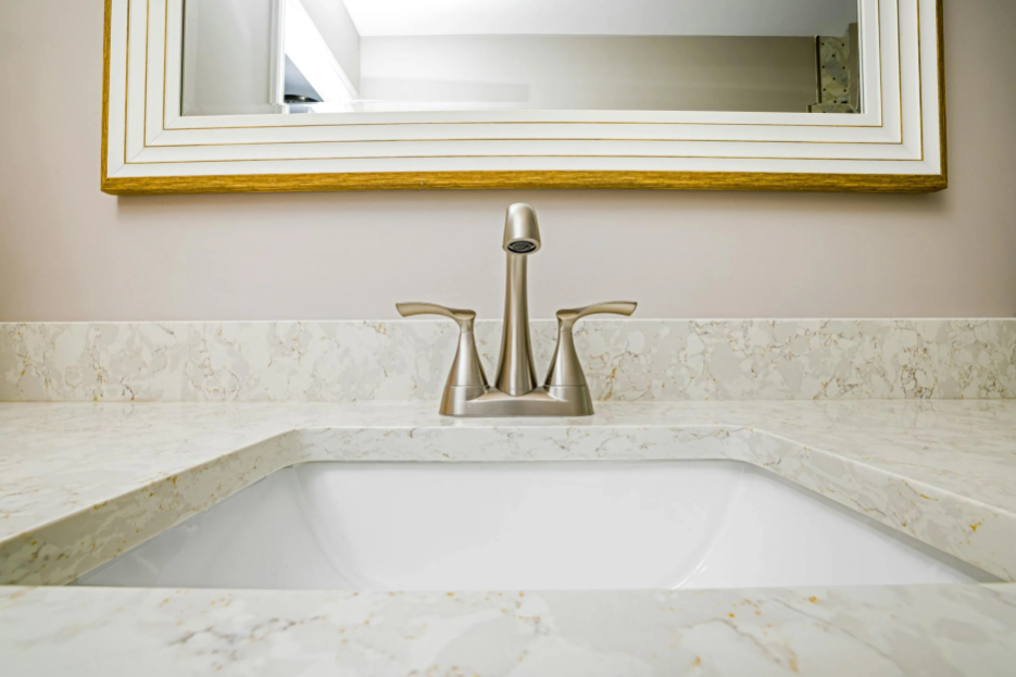 A bathroom with a custom quartz vanity top, modern fixtures, and elegant lighting.