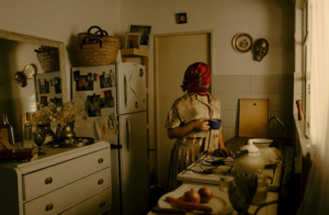 Lady standing by a window in a vintage kitchen, enjoying tea amidst classic surfaces and historical design.